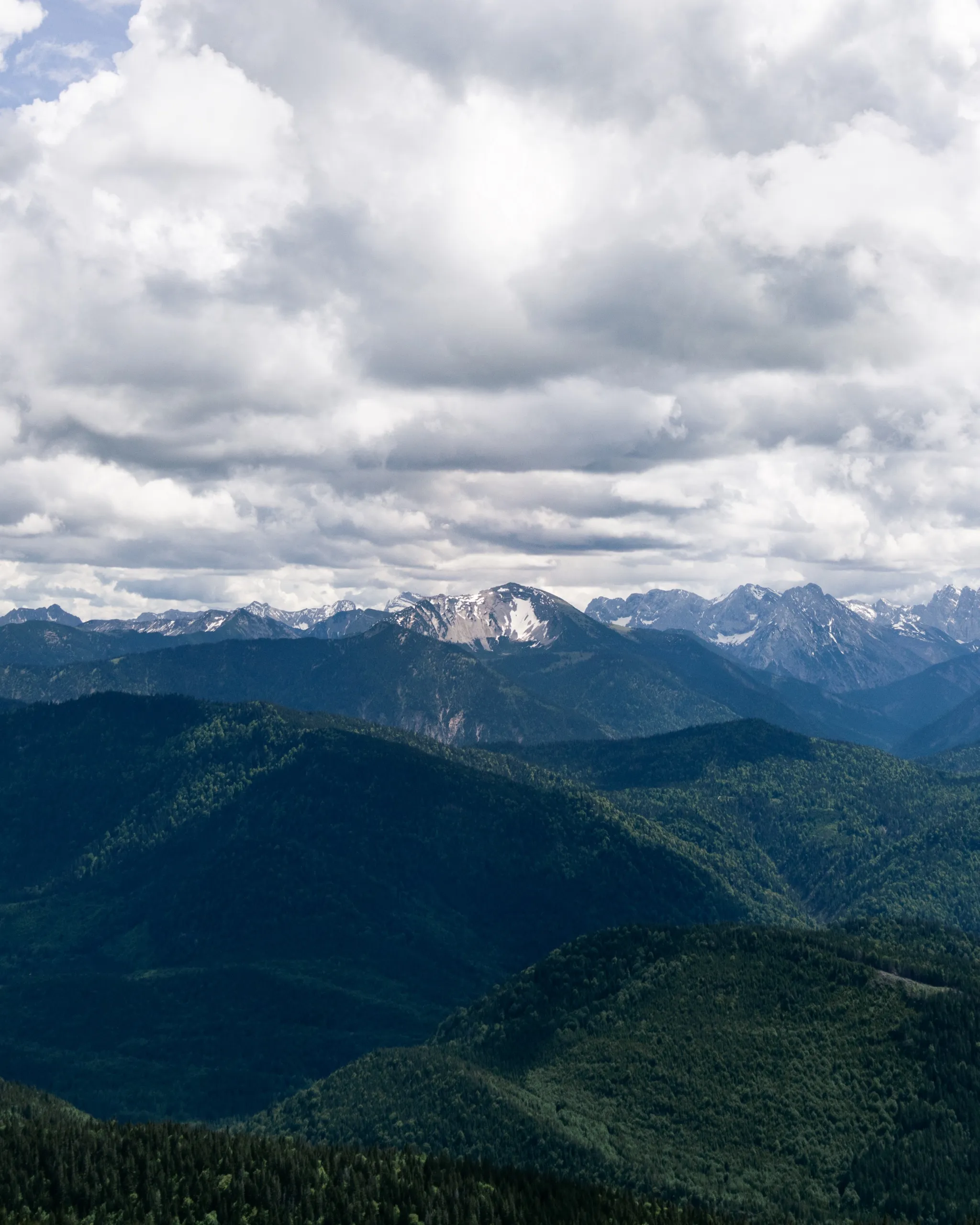 Forested valleys and mountain ridges under scattered clouds