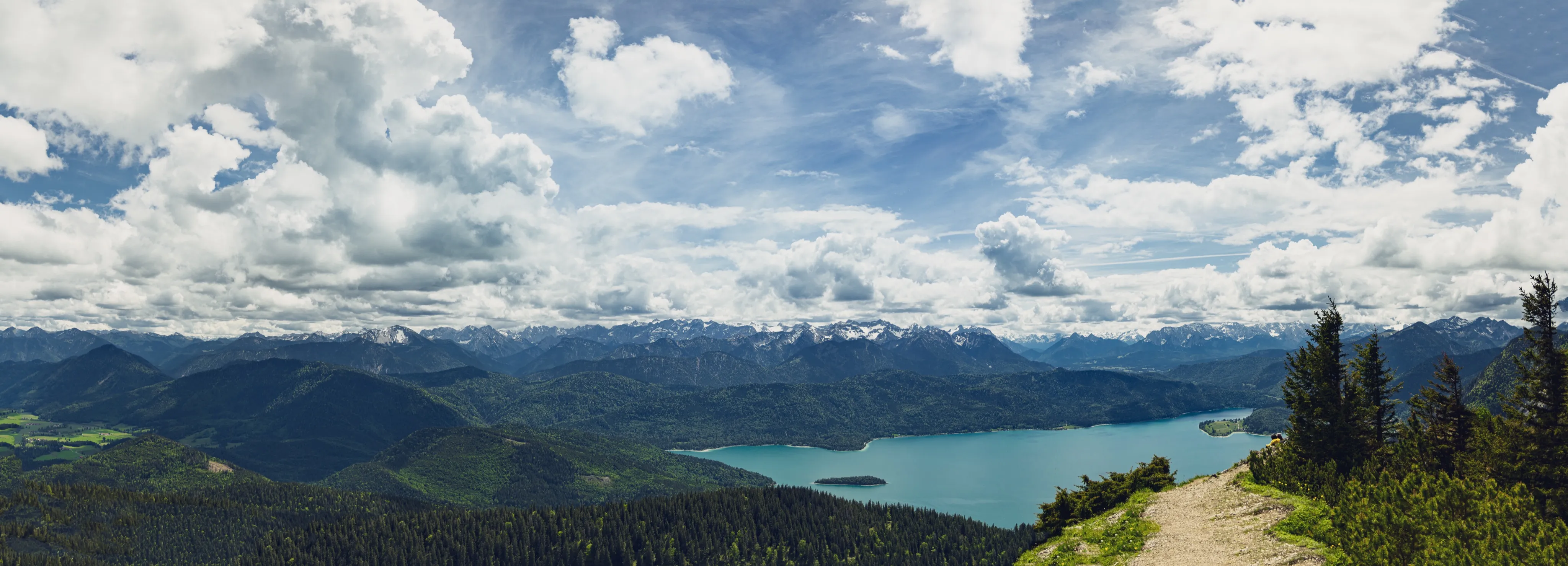 Panorama of a mountain lake seen from a forest trail