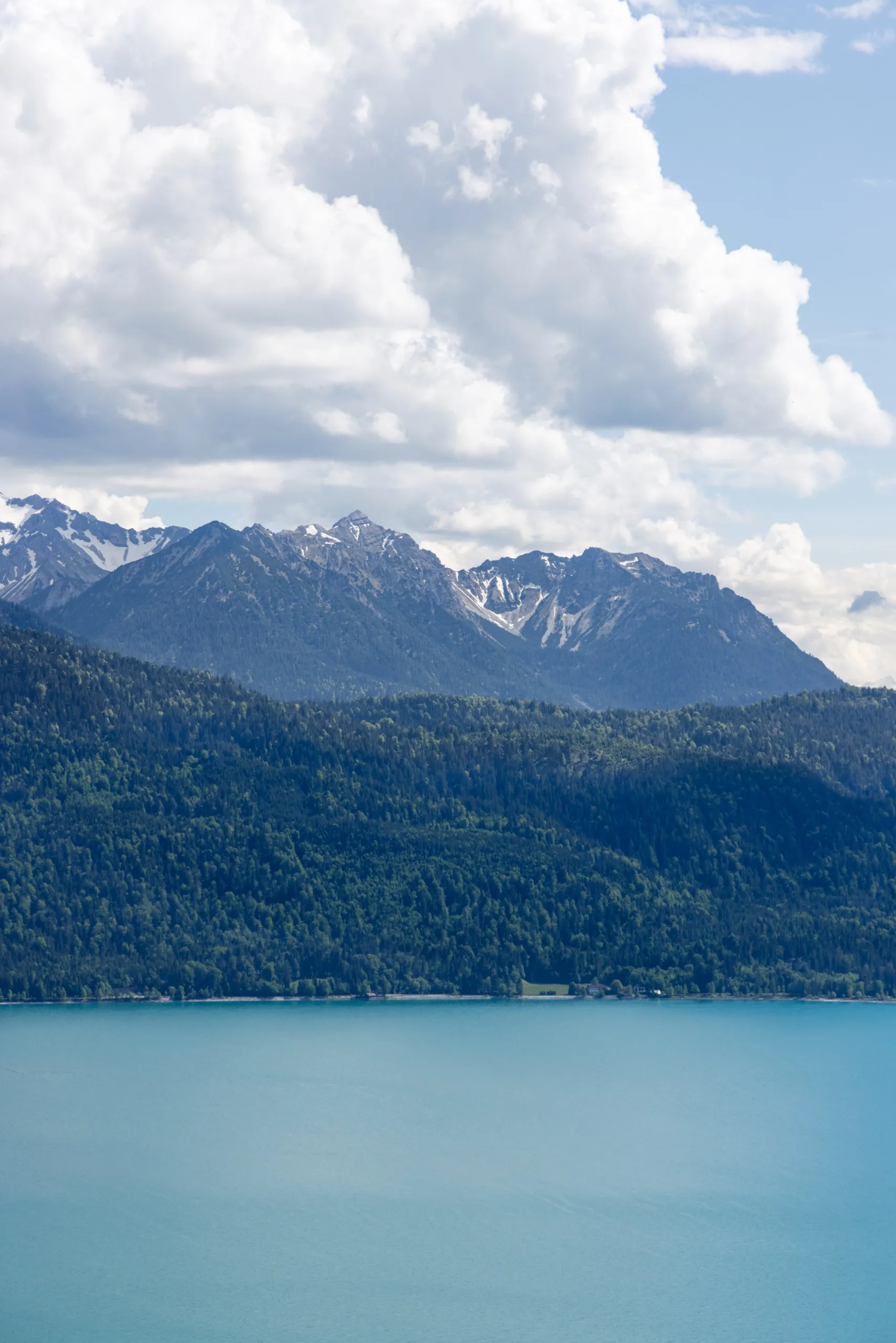 A lake framed by mountains under a tall sky of white clouds